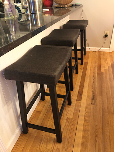 Amisco's Miller Backless Saddle Counter Stool in Black Metal Finish Shown in Transitional Kitchen with Hardwood Flooring